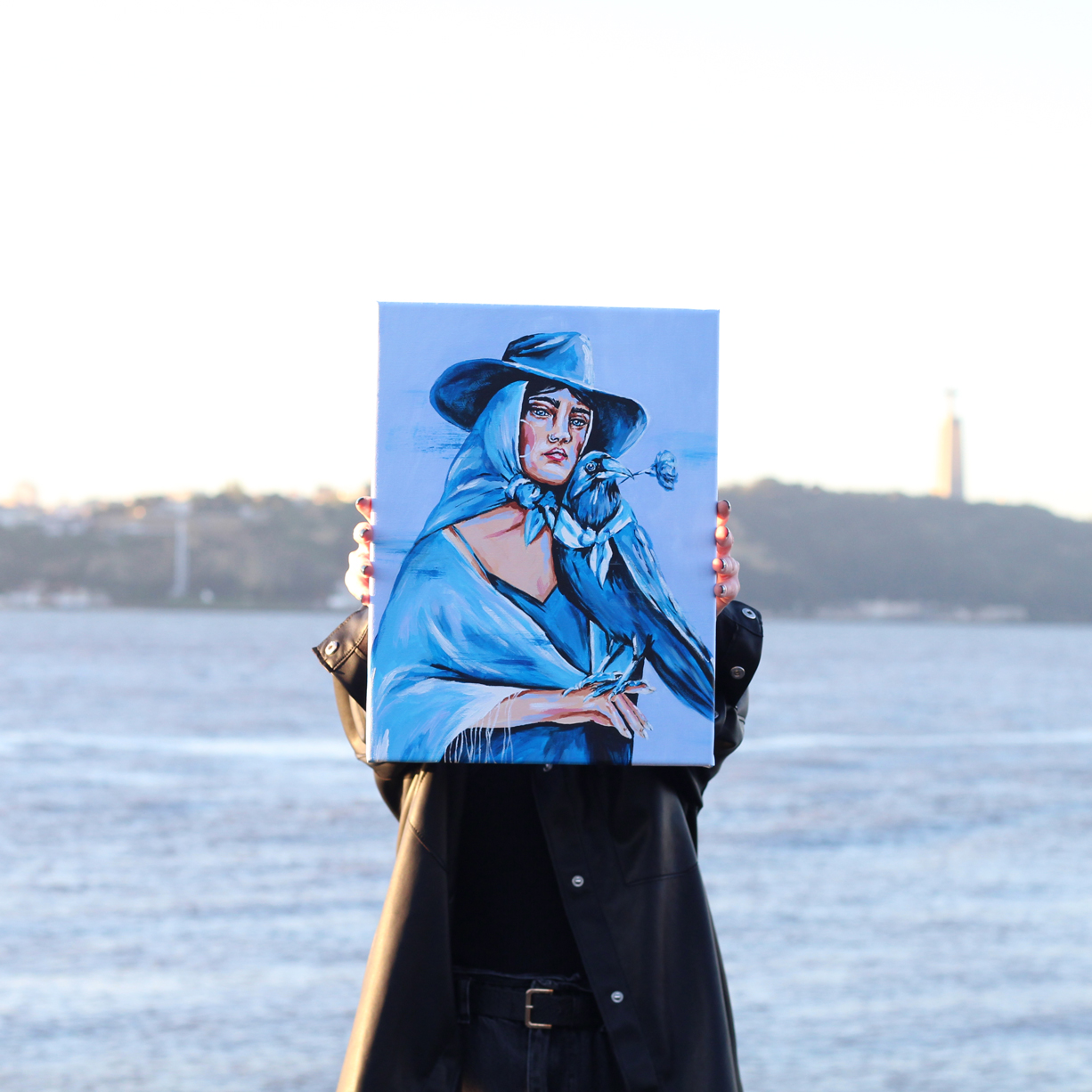 carmo-tela-marita-apaixonarte02 Someone holding a painting of young woman and by Marita on a pier.